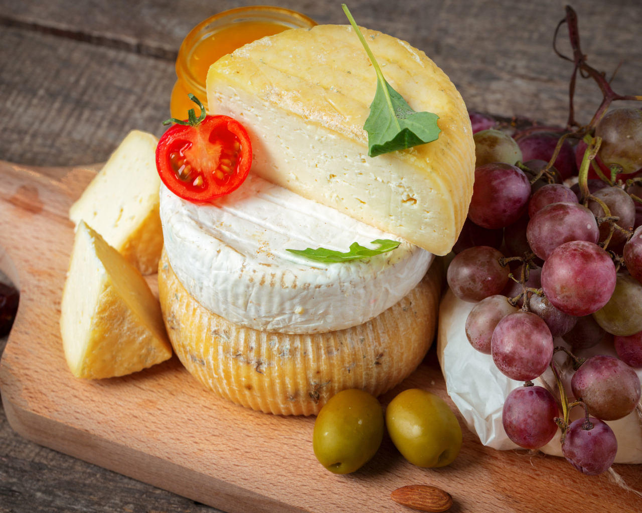 Сыр на разделочной доске с виноградом и оливками