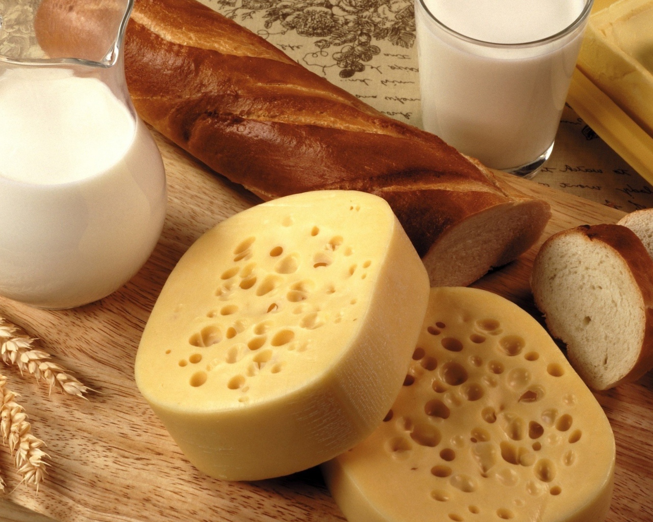 Сыр на столе с маслом, молоком и батоном 