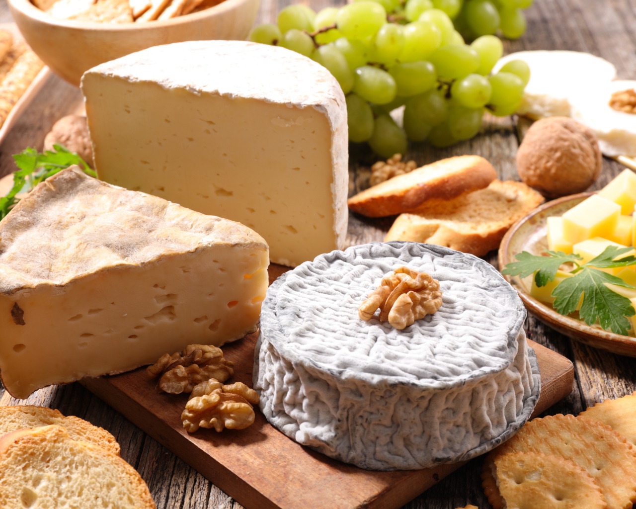 Сыр с плесенью на столе с виноградом, орехами и хлебом