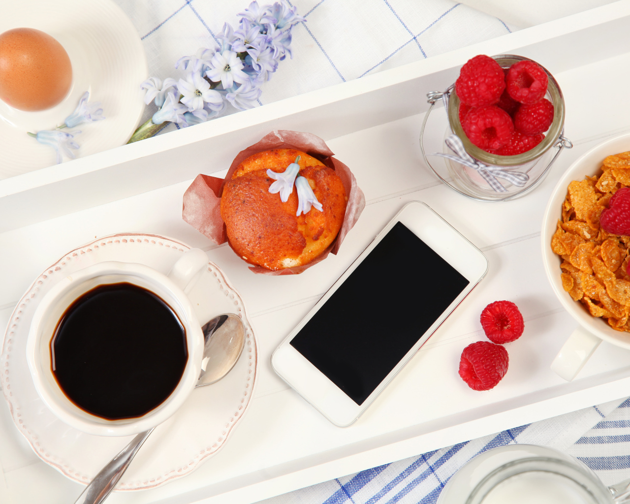 Кофе с кексом, хлопьями и малиной на столе со смартфоном 