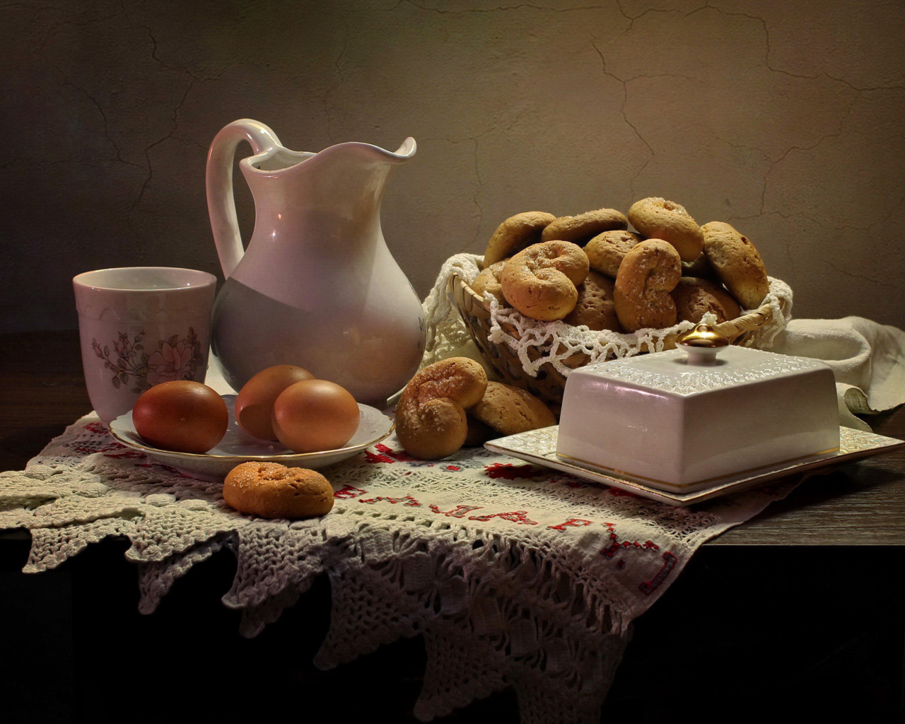 Вареные яйца на столе с кувшином, выпечкой и масленкой 