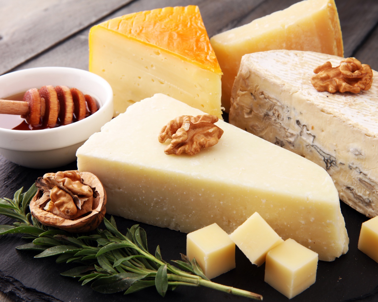 Разные виды сыра на столе с медом и грецкими орехами