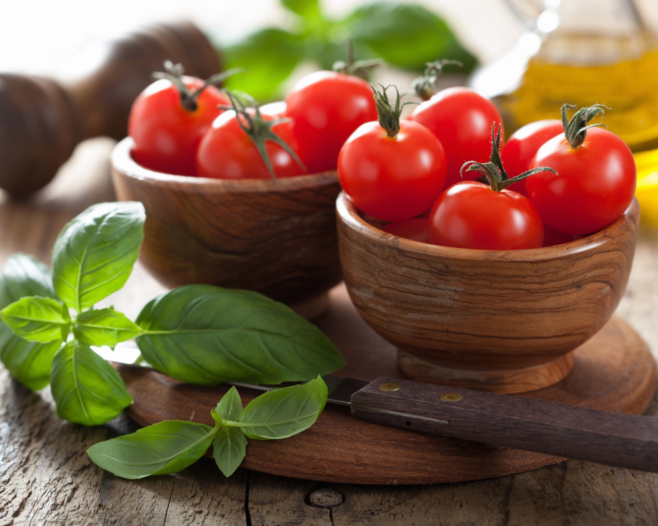 Свежие красные помидоры на столе в деревянных мисках с базиликом