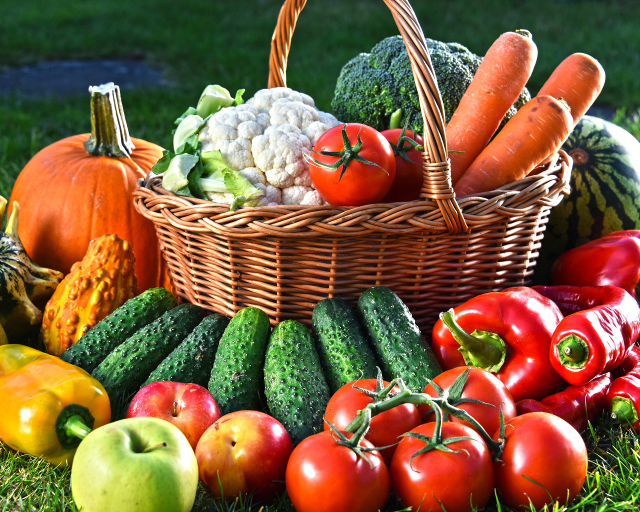 Свежие овощи и фрукты в корзине на зеленой траве