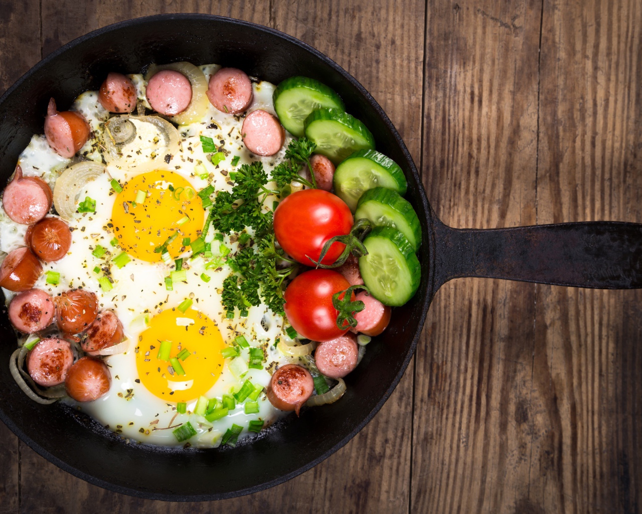 Яичница в сковороде с овощами и кусочками сосиски