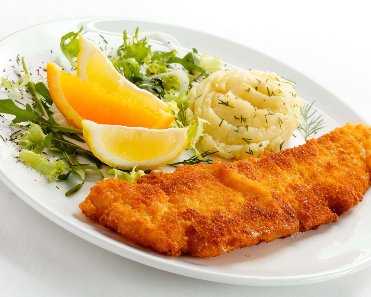 Картофельное пюре с мясом, кусочками апельсина и салатом на тарелке