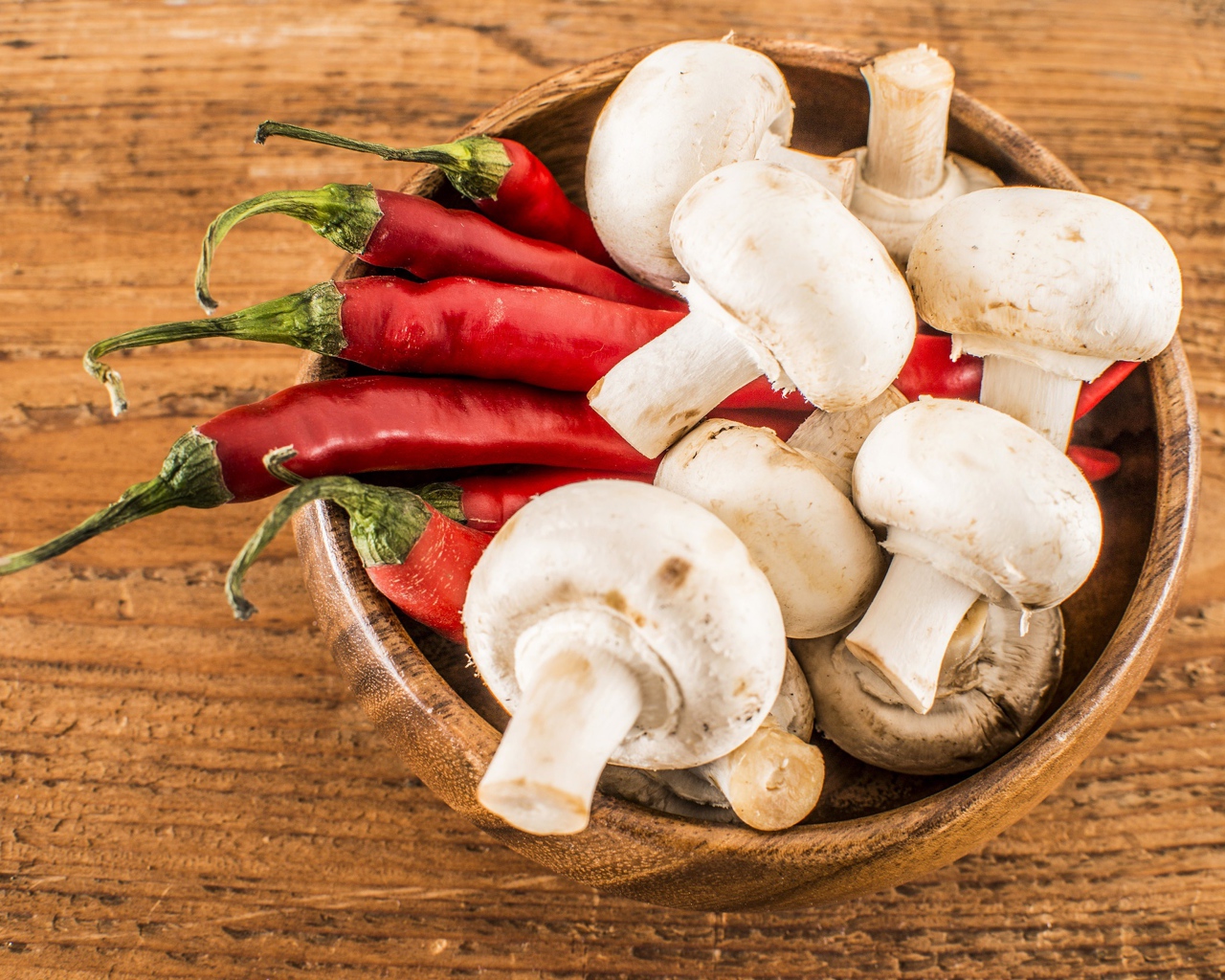 Грибы шампиньоны в деревянной миске с красным перцем