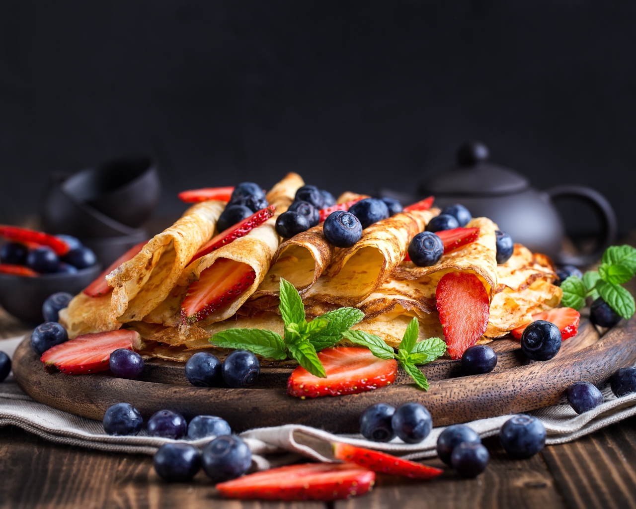 Блинчики с ягодами черники и клубники на столе