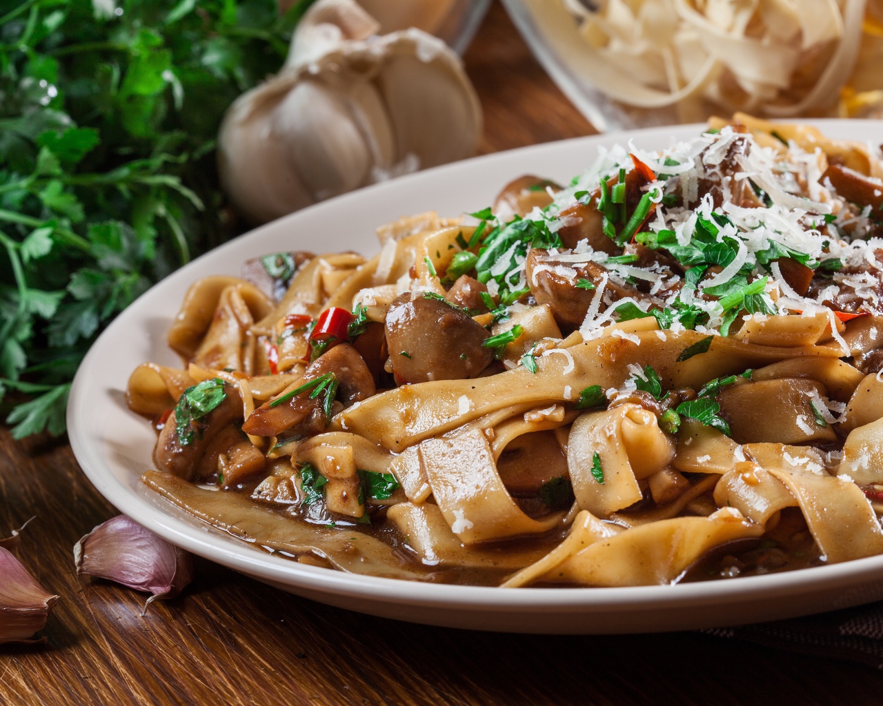 Паста с грибами, сыром и  зеленью на столе с чесноком 