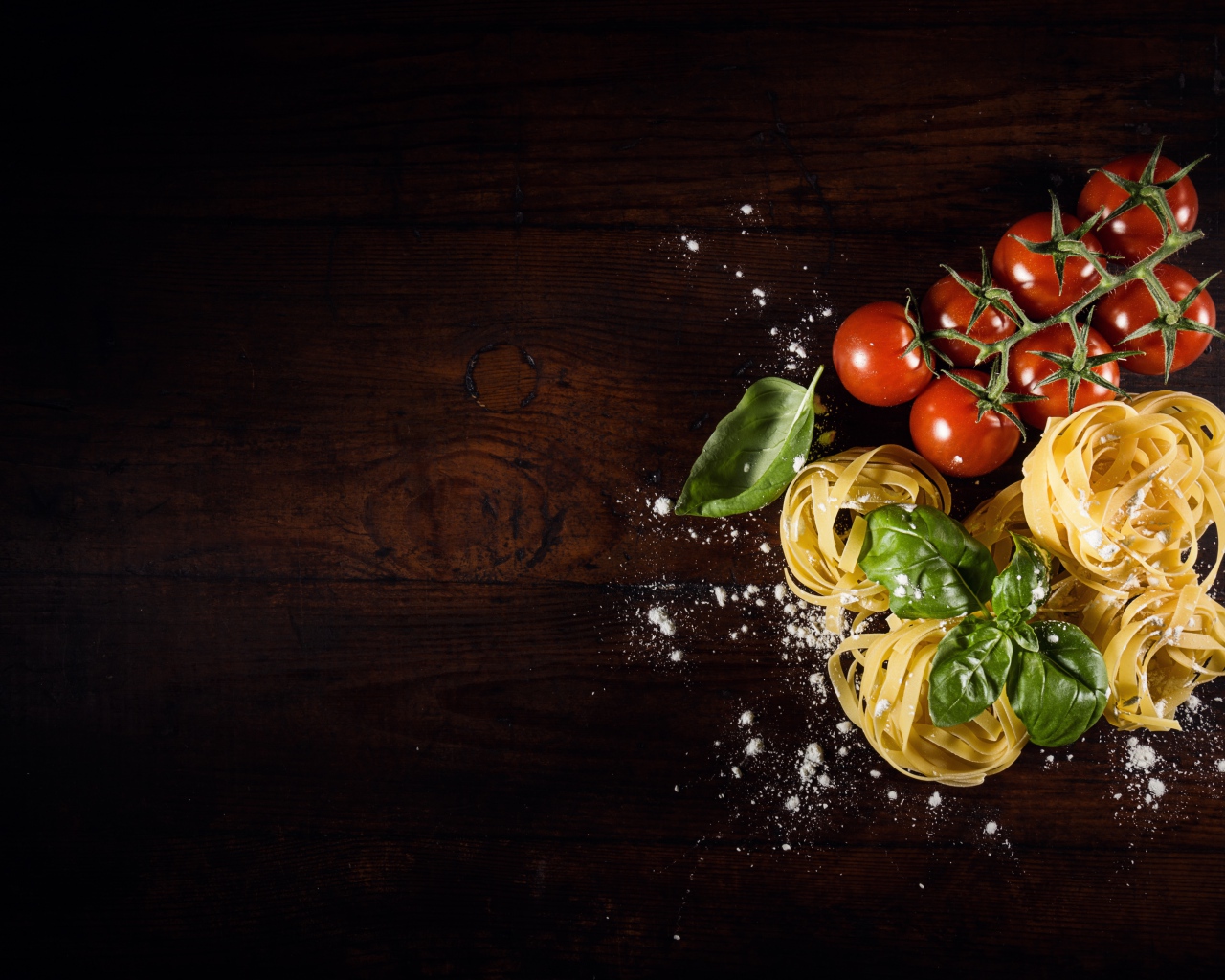 Паста с помидорами и листьями базилика на столе