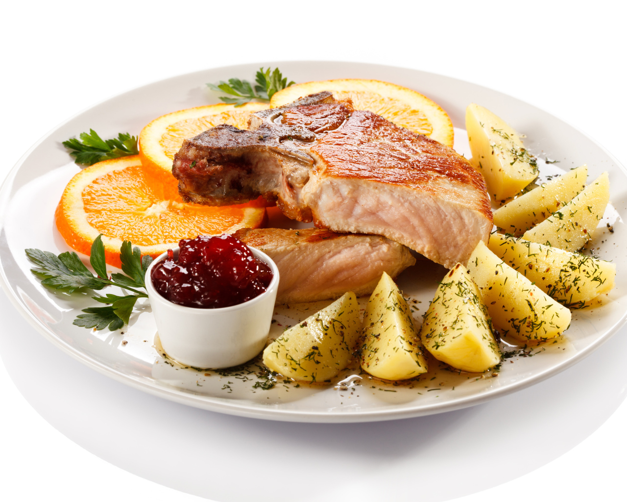 Картофель с мясом и кусочками апельсина на тарелке
