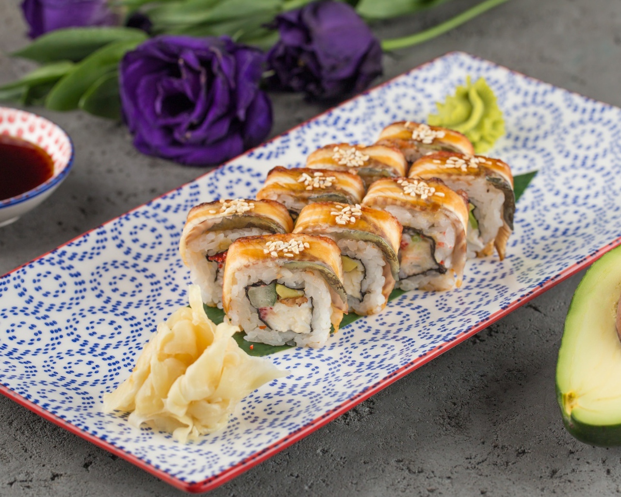 Роллы с авокадо и соевым соусом на столе с цветами 