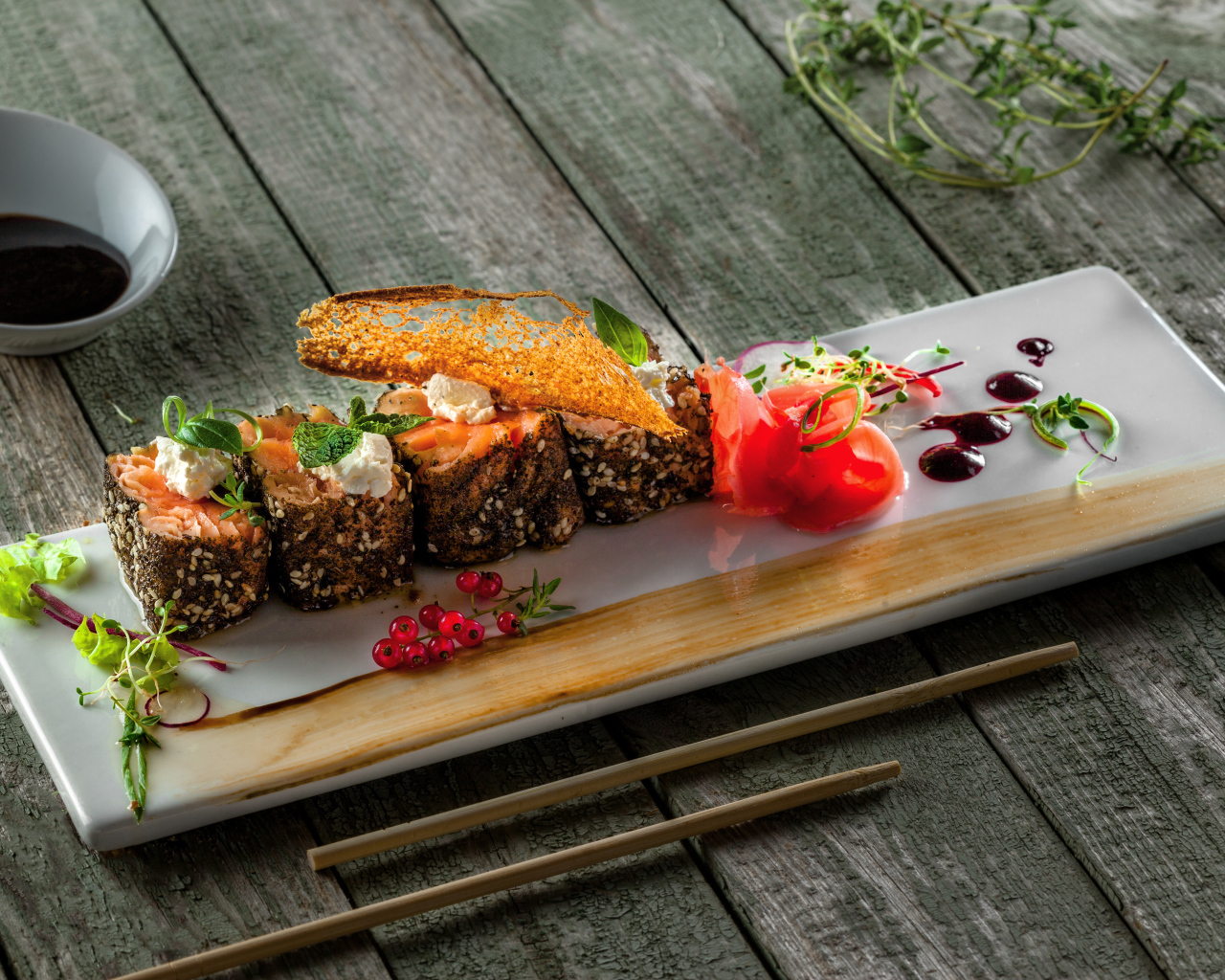 Суши на тарелке на деревянном столе с соусом