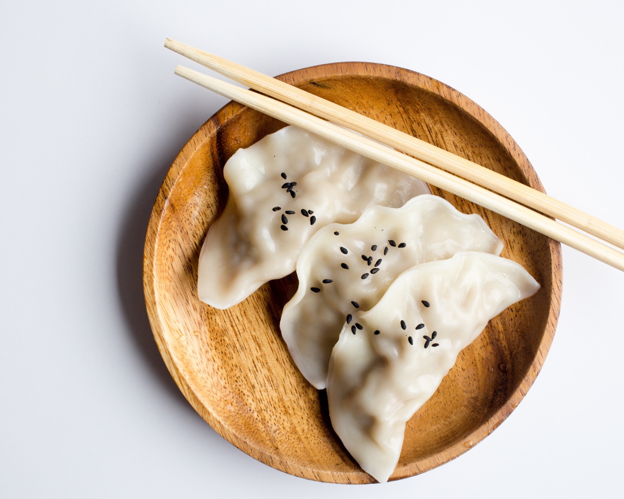 Три вареника на деревянной тарелке с палочками