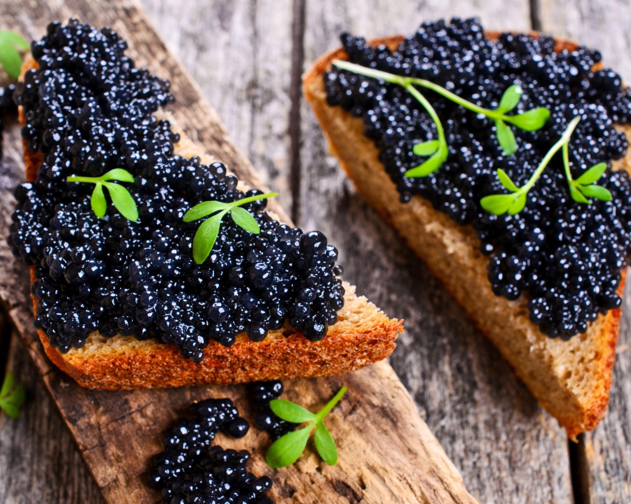 Два аппетитных бутерброда с черной икрой на деревянном столе