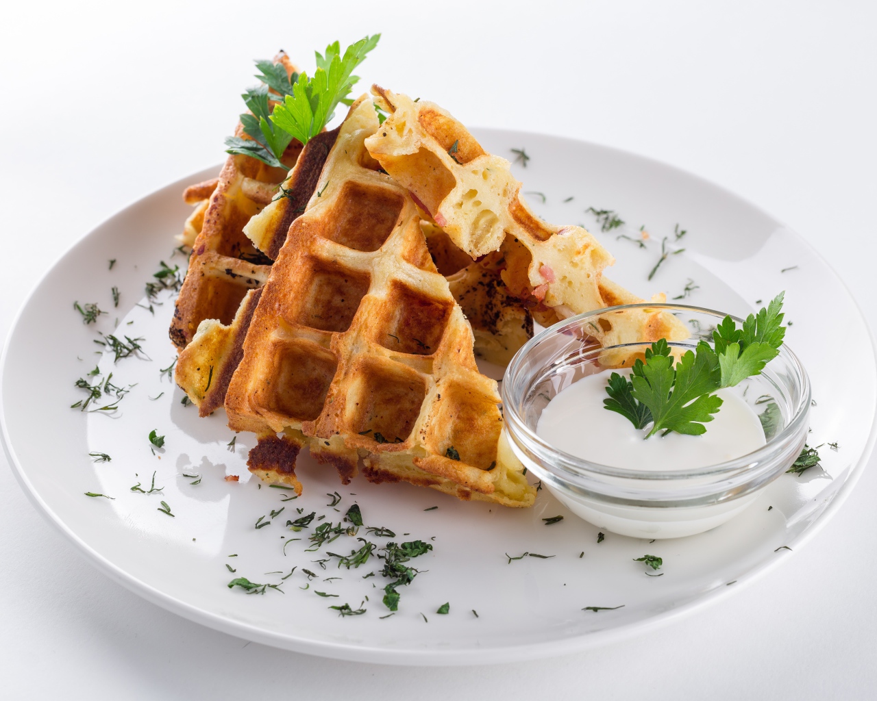 Несладкие вафли на белой тарелке с зеленью и соусом
