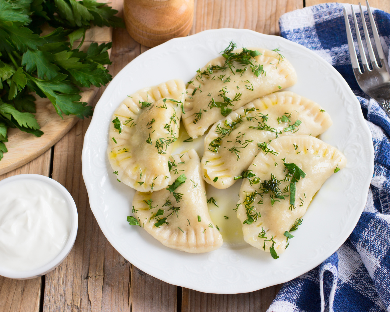 Вареники с зеленью на белой тарелке 