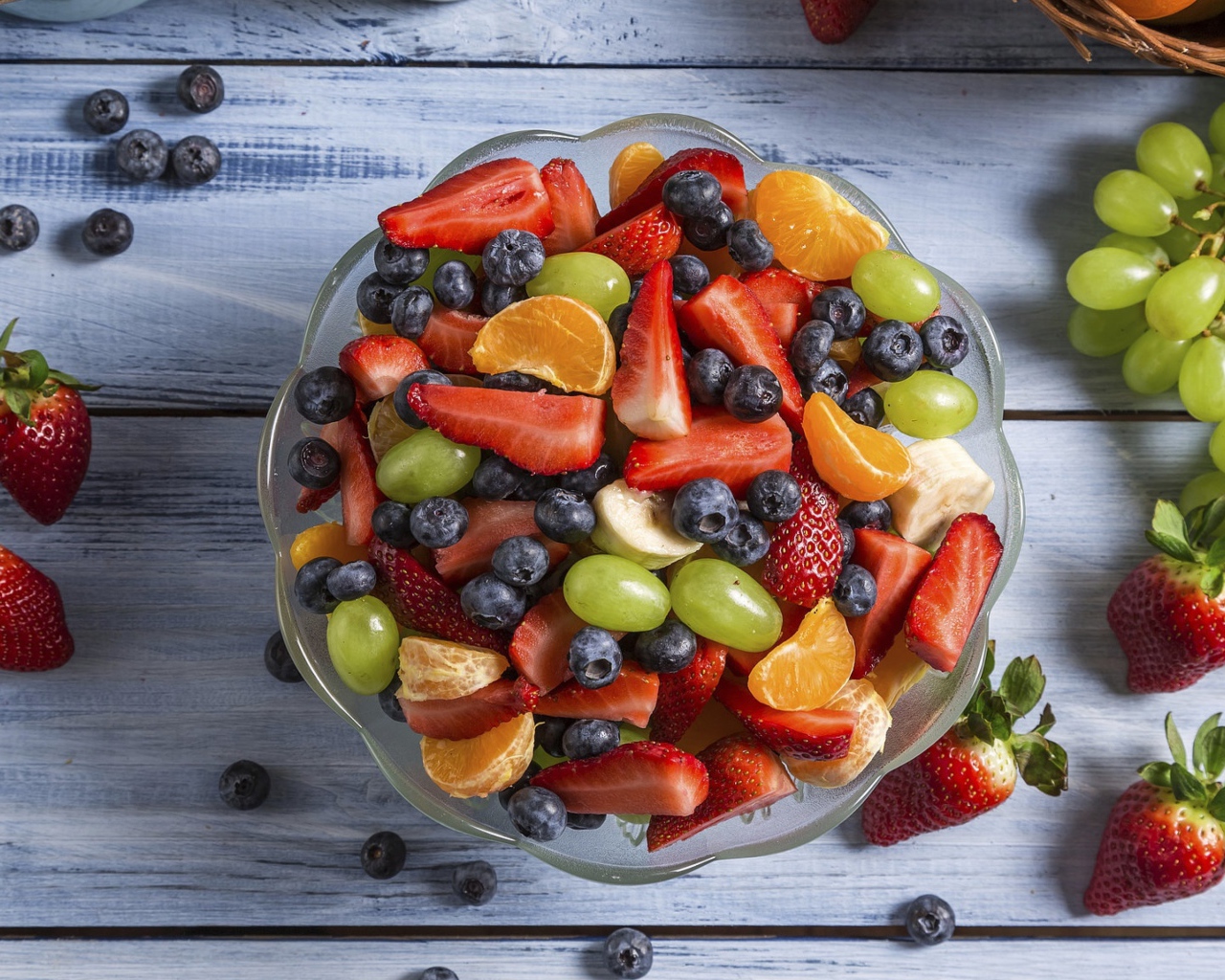 Фрукты и ягоды в тарелке на столе 