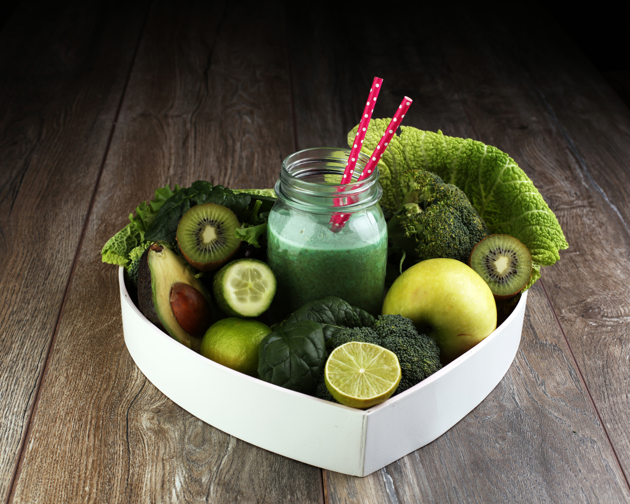 Зеленые овощи и фрукты в тарелке с баночкой смузи