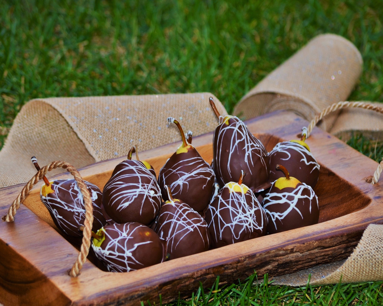 Груши в шоколадной глазури стоят на зеленой траве