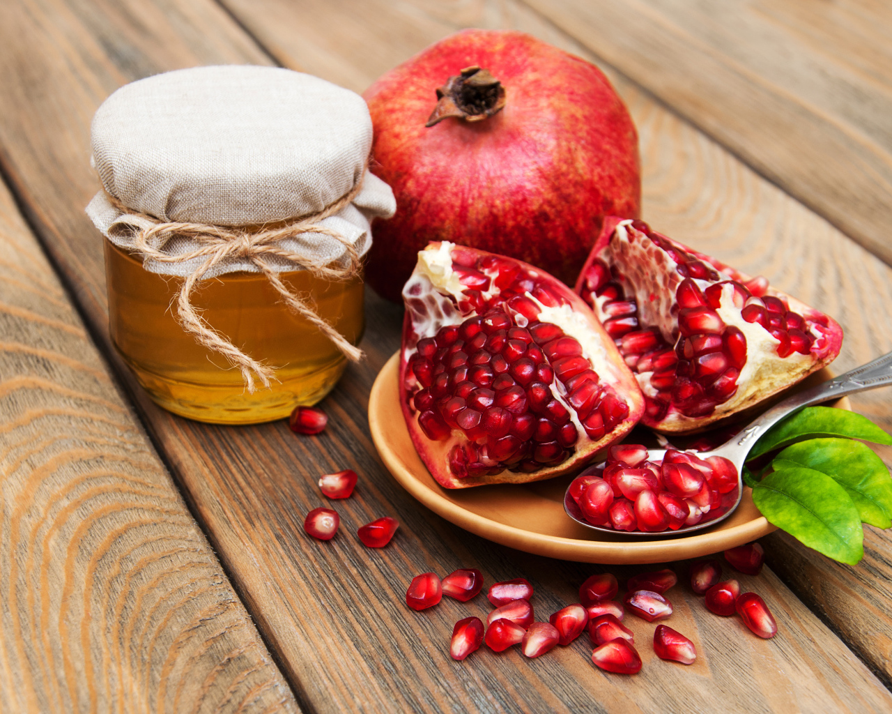 Гранат на деревянном столе с банкой меда