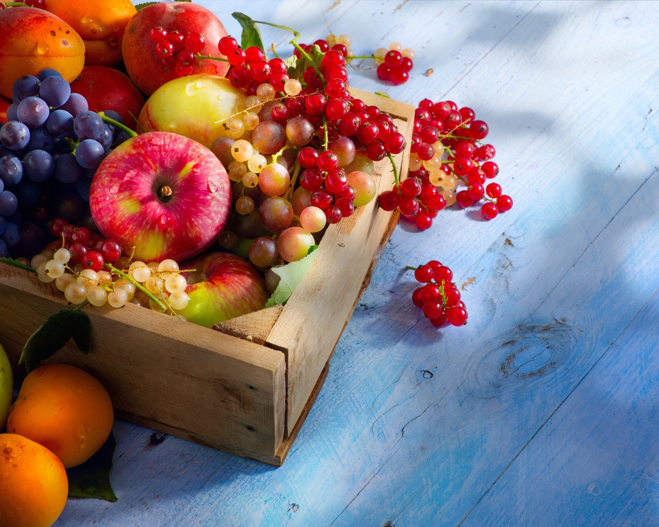 Спелые сочные ягоды и фрукты на столе в деревянном ящике