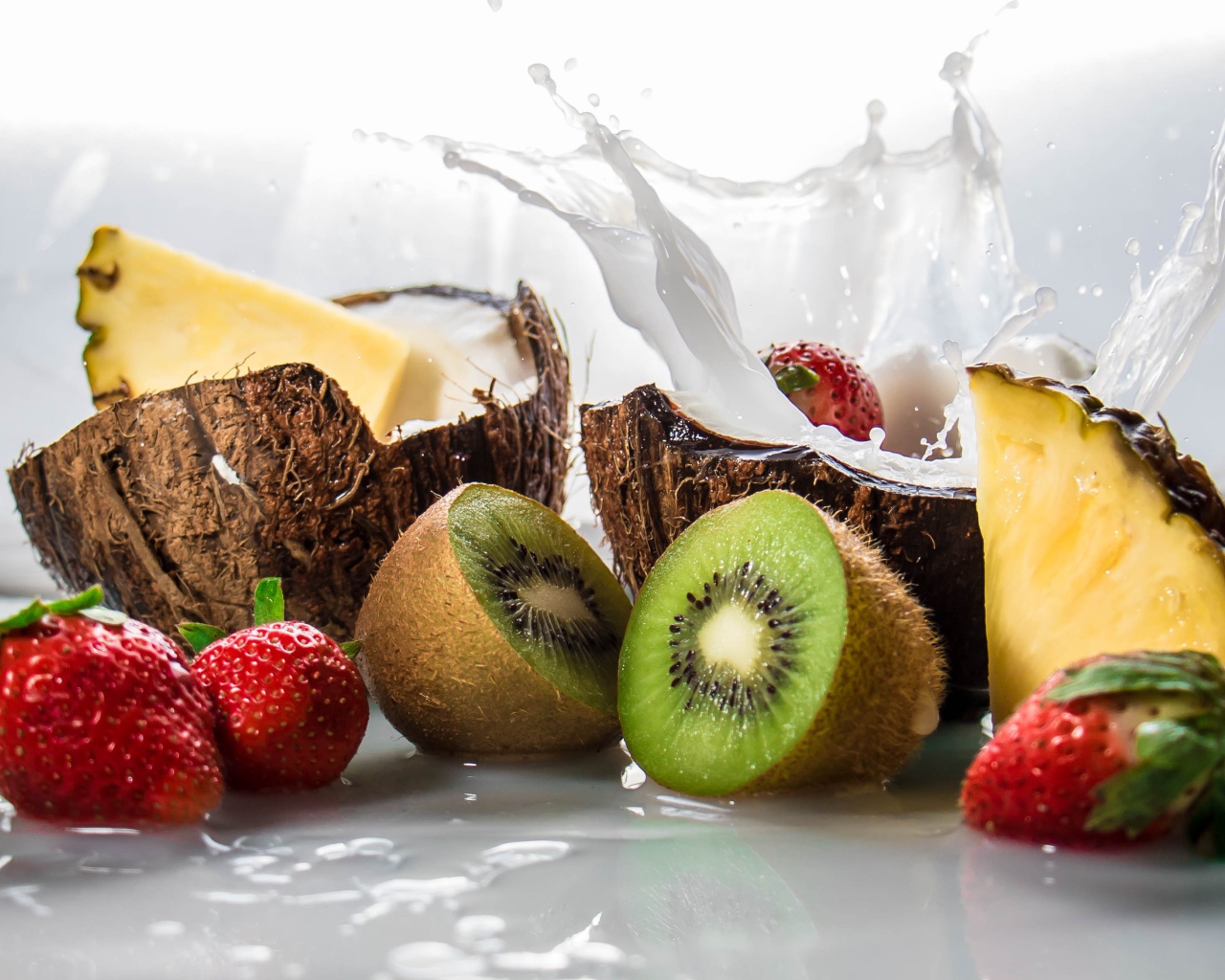 Тропические фрукты кокосы, ананасы и киви на белом фоне с клубникой