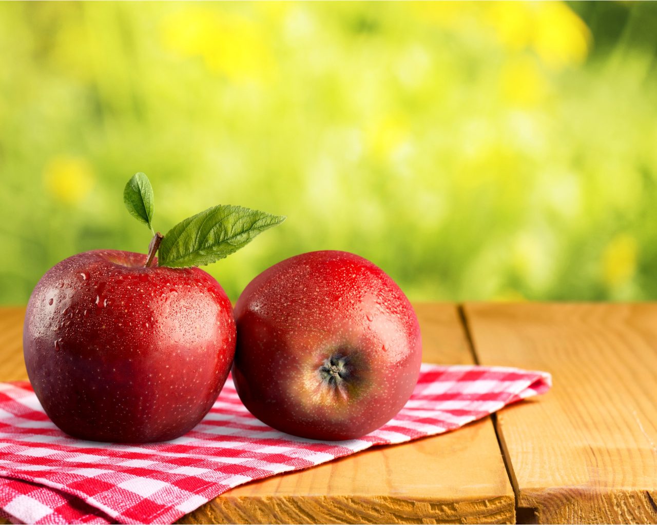 Два красных яблока в каплях воды лежат на полотенце 