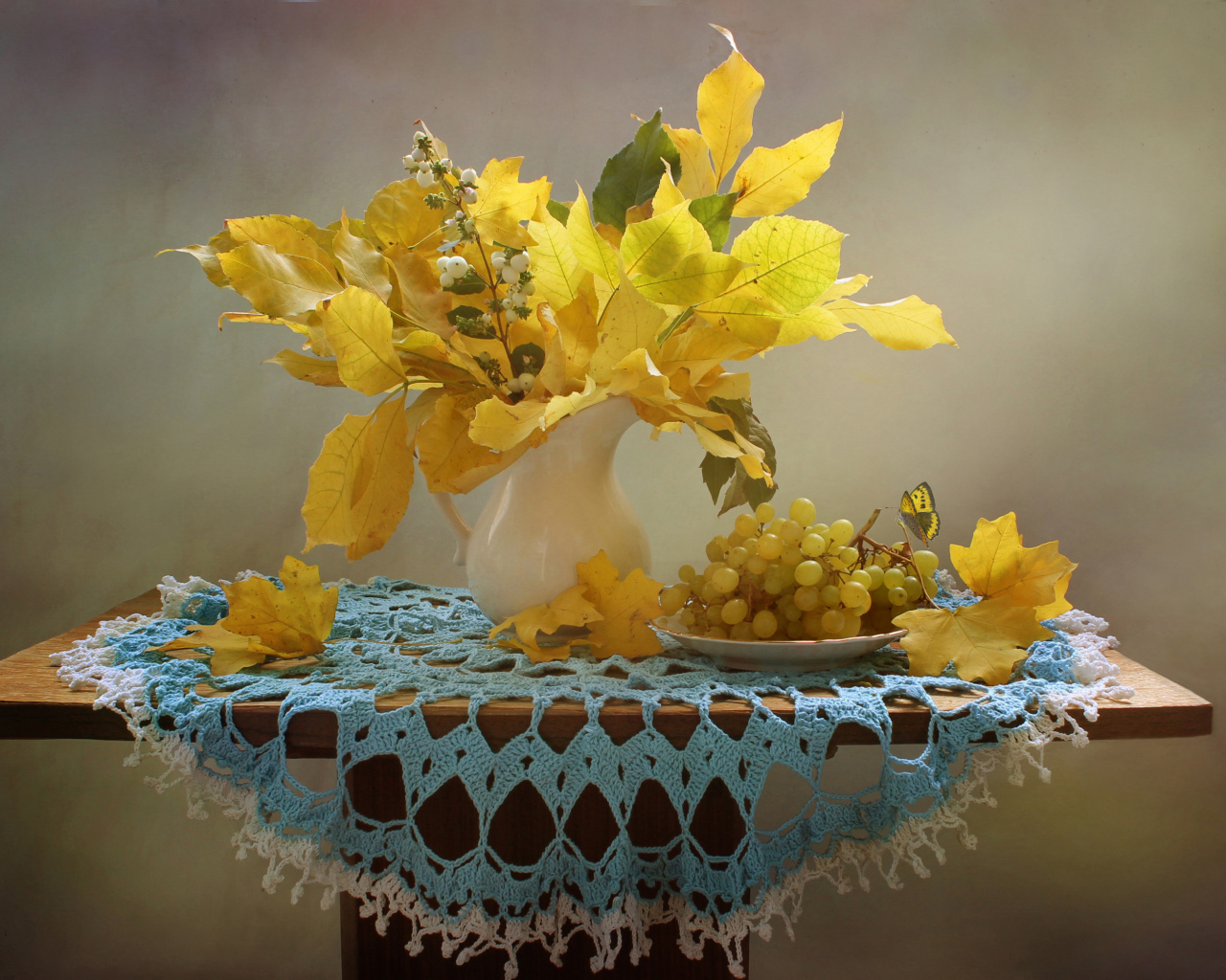 Белый виноград на столе с желтыми осенними листьями