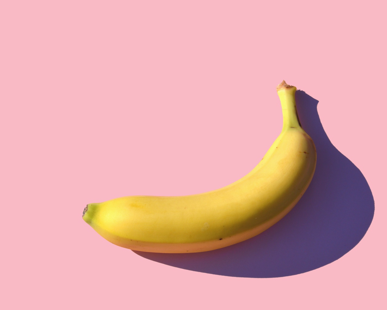 Желтый банан на розовом фоне