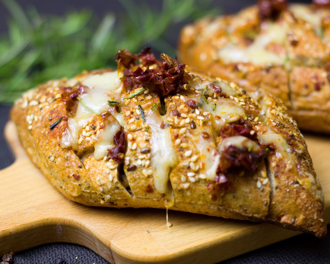 Булочка с кунжутом и сыром на разделочной доске 