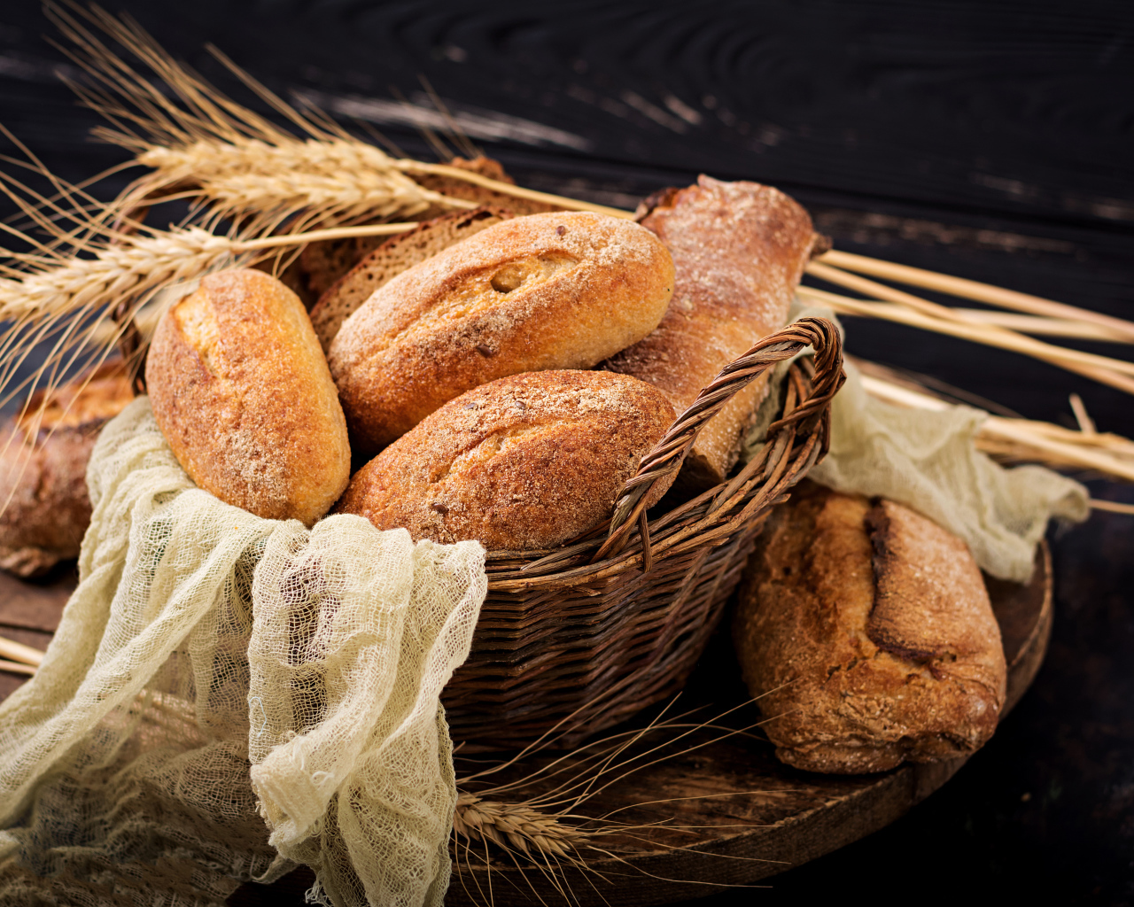 Свежая выпечка в корзине на столе с колосьями пшеницы