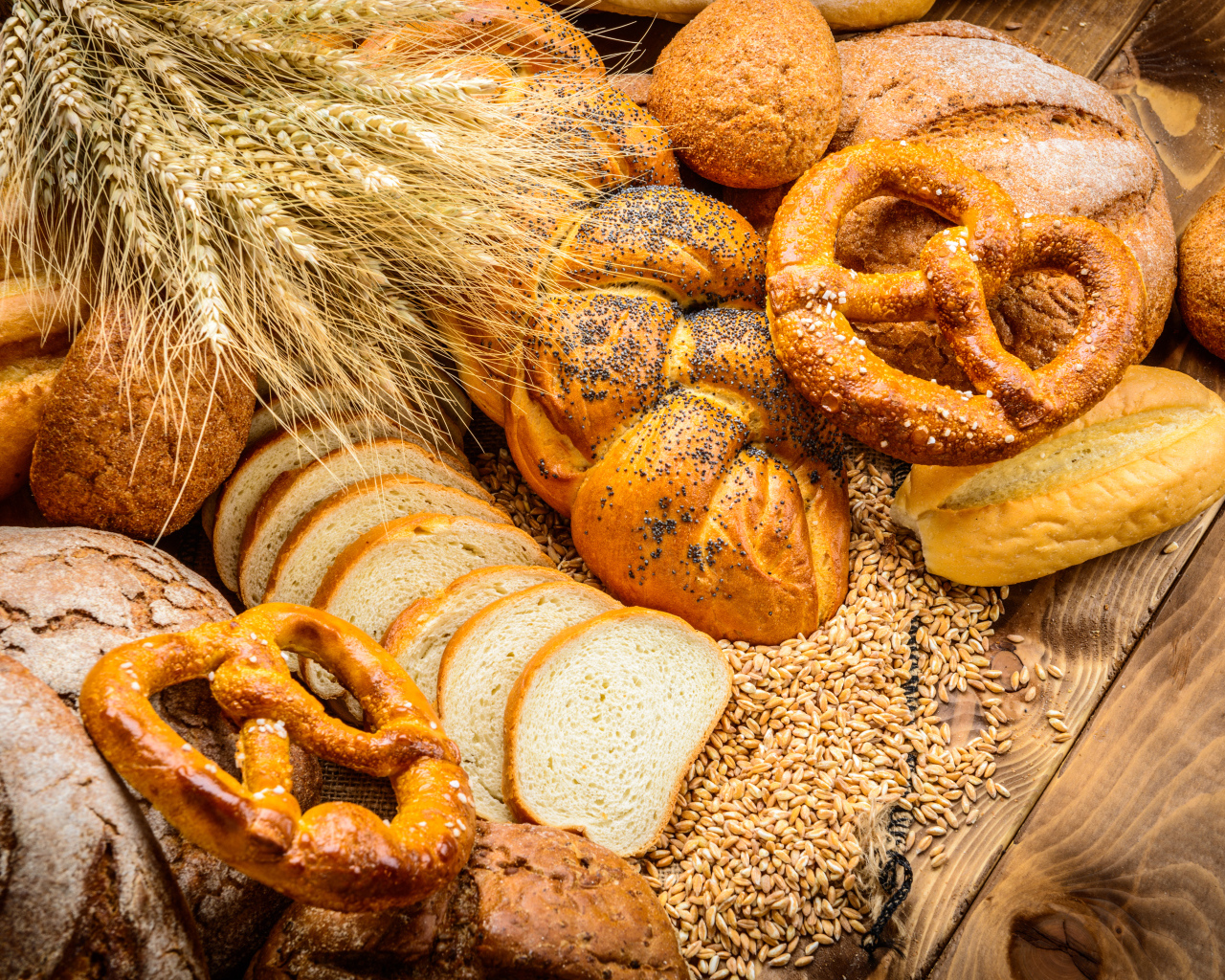 Свежая выпечка с колосьями и зернами пшеницы на столе 