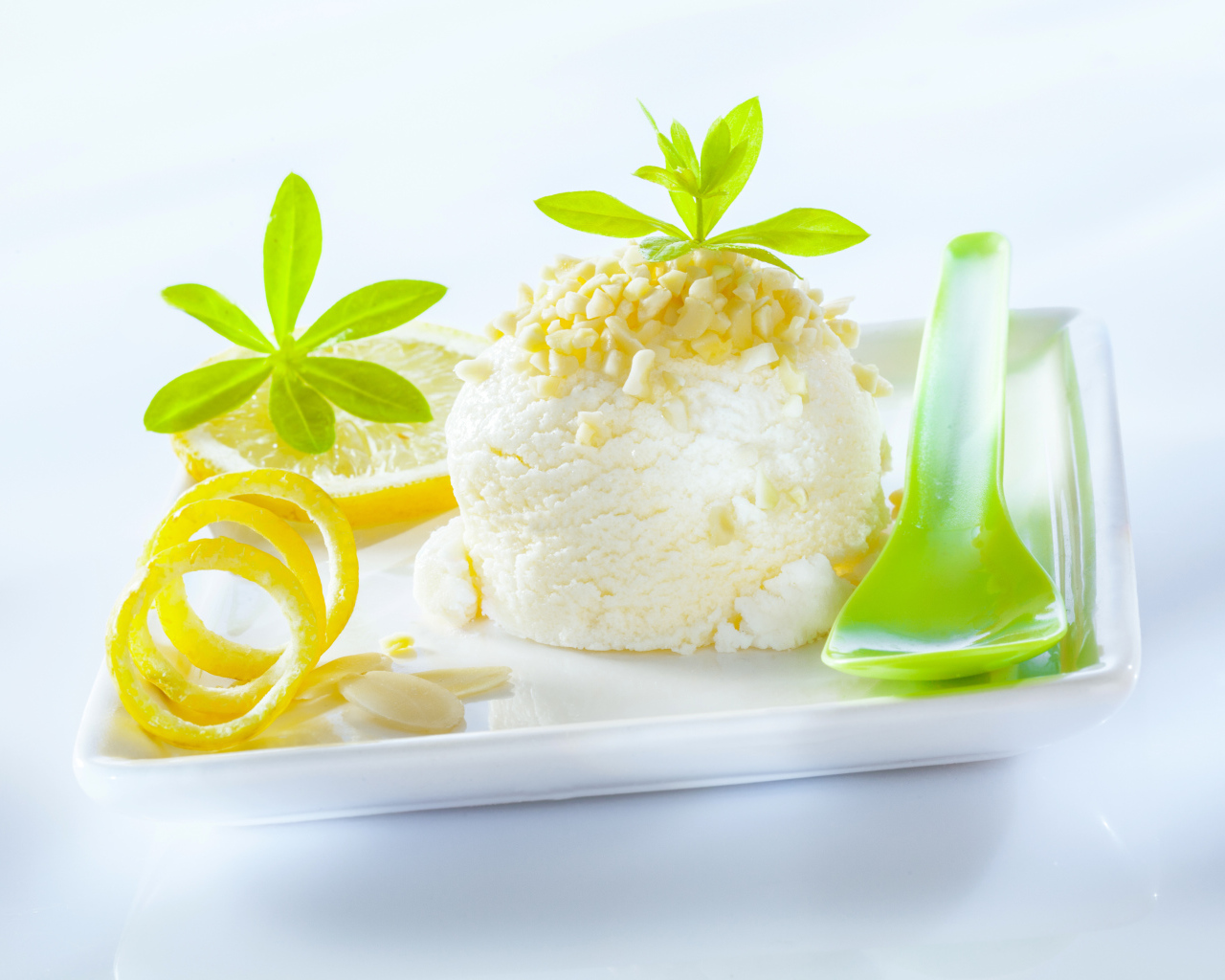 Шарик лимонного мороженого с фисташками с зеленой ложкой