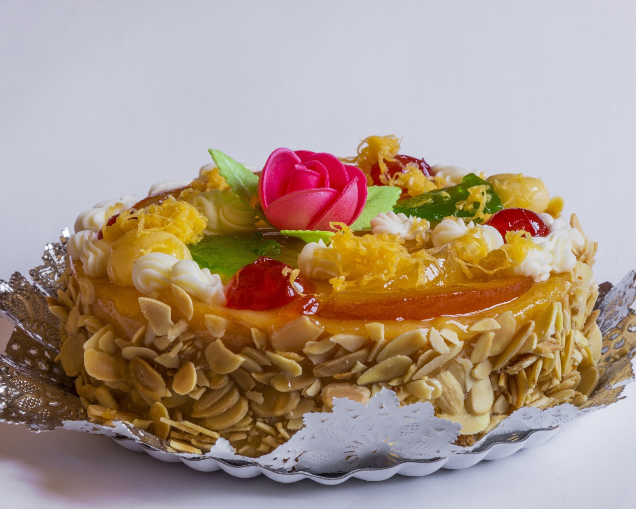 Красивый торт с кремом и ягодами украшен розовым цветком