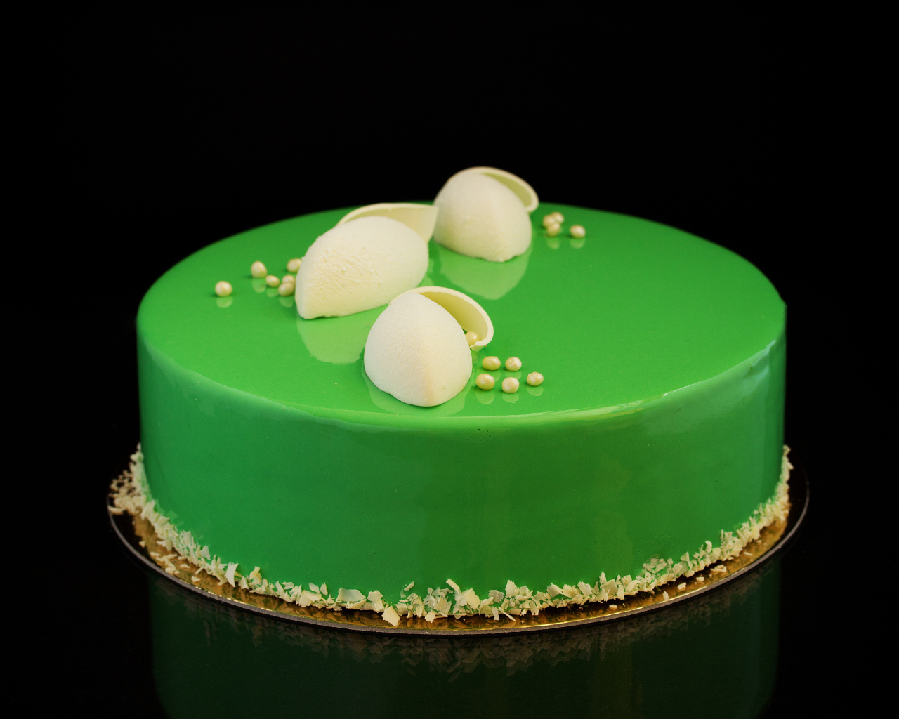 Зеленый глянцевый торт отражается в черной поверхности 