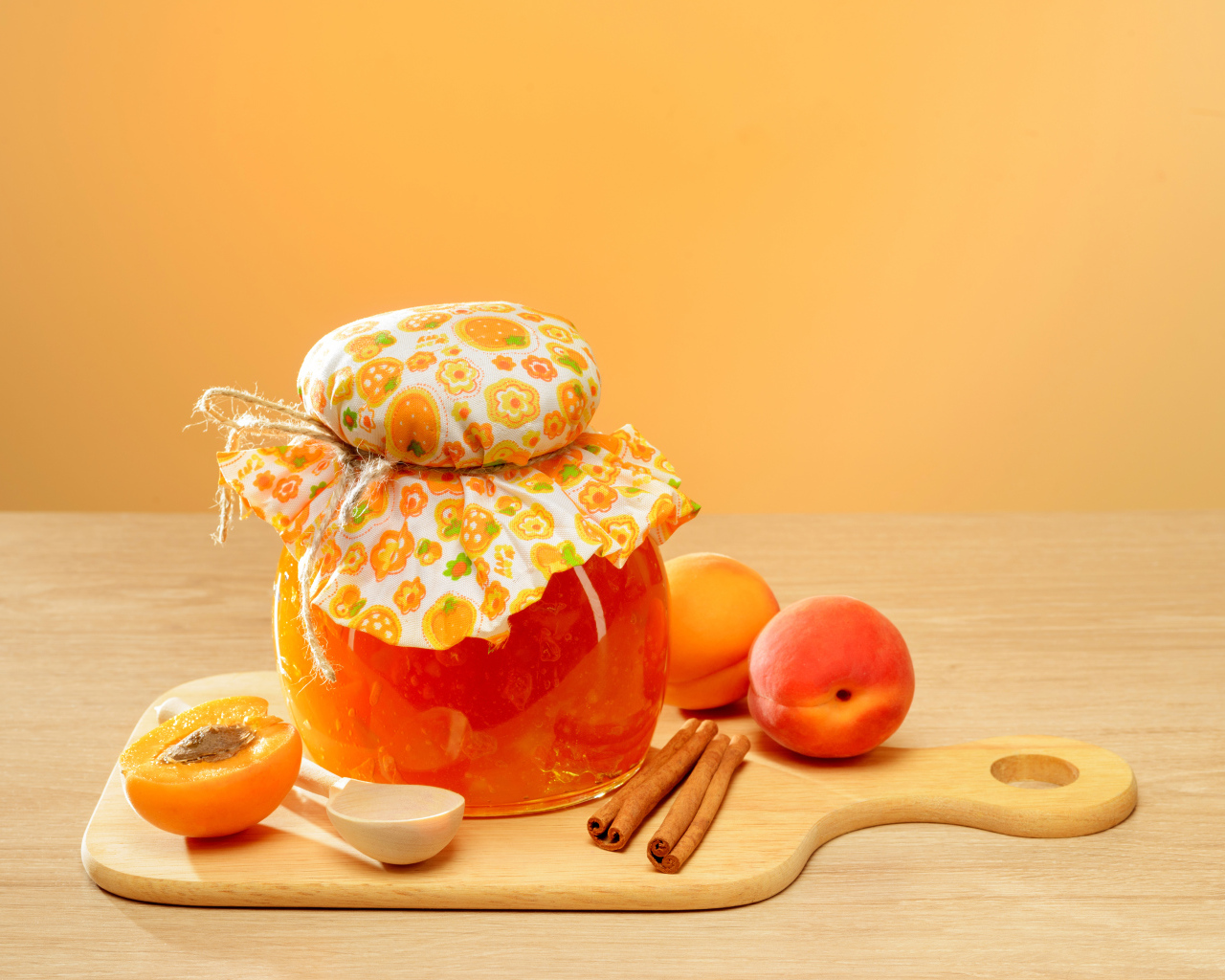 Банка абрикосового джема на столе с фруктами