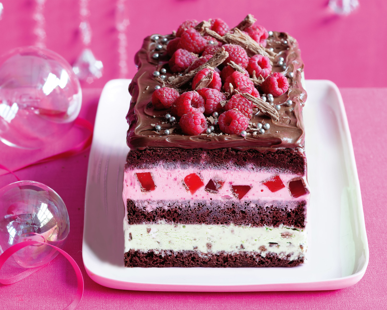 Кусок пирога с шоколадом и малиной на розовом фоне