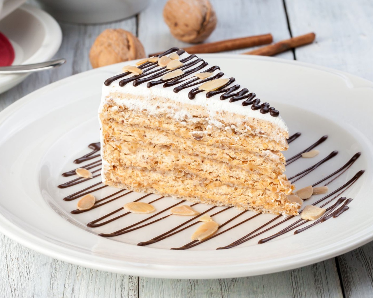 Кусок торта с орехами и шоколадом на белой тарелке