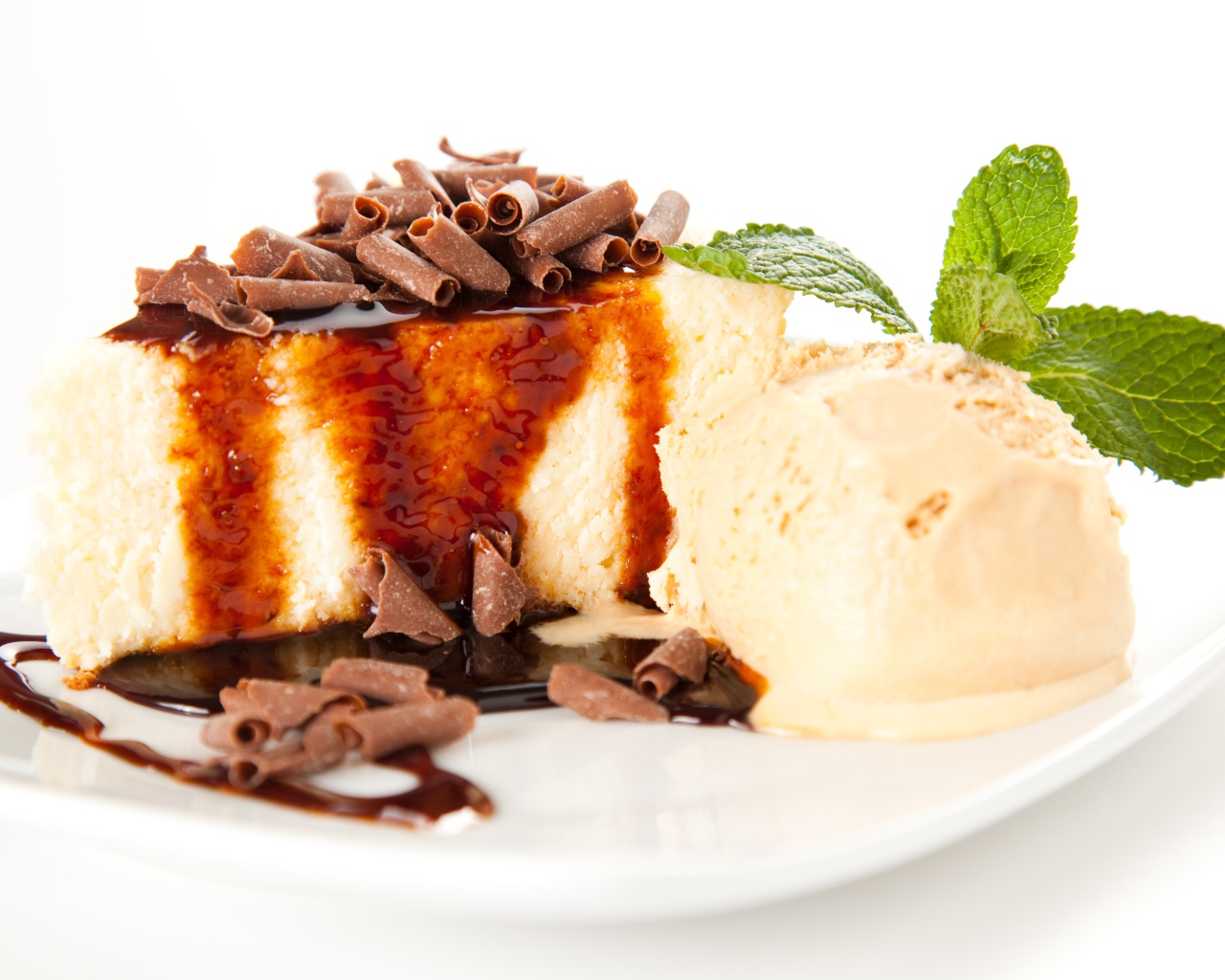 Кусок чизкейка с шоколадом и шариком мороженого на белой тарелке 