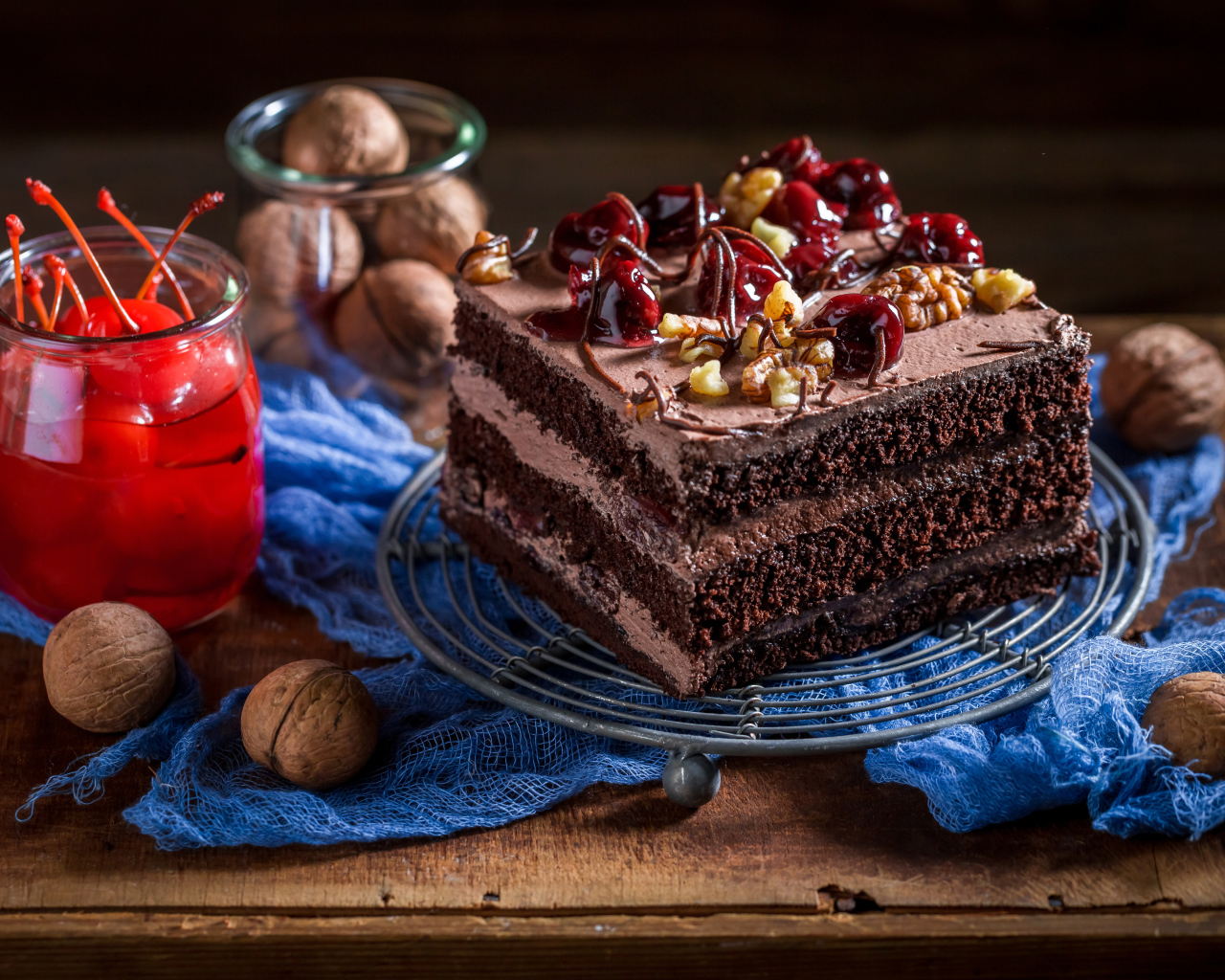Кусок шоколадного торта на столе с вишнями и грецкими орехами