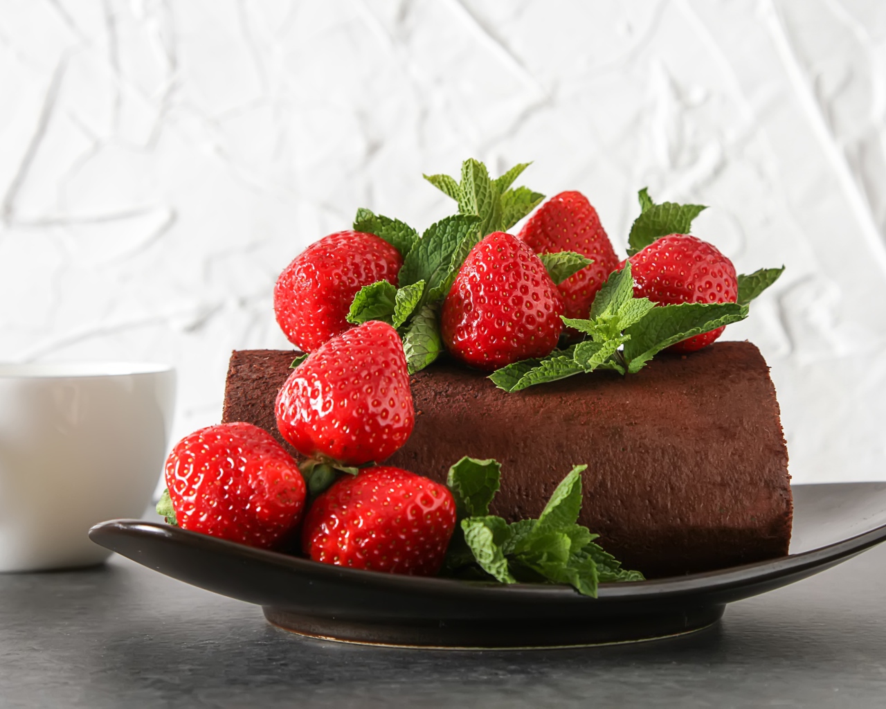 Кусок шоколадного торта со свежей клубникой на тарелке