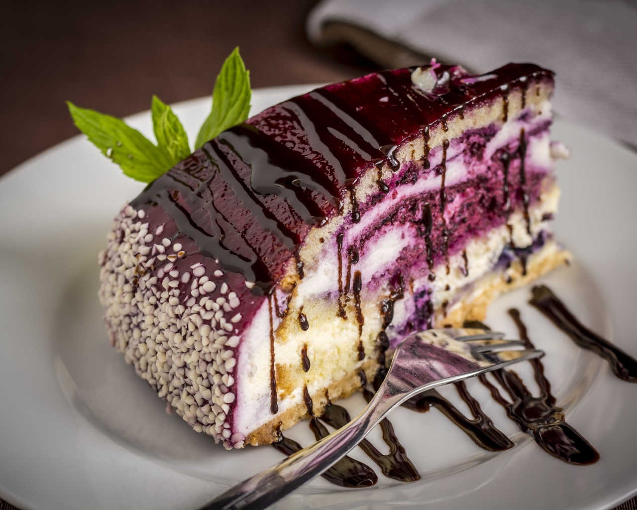 Кусок черничного пирога с джемом на белой тарелке с вилкой