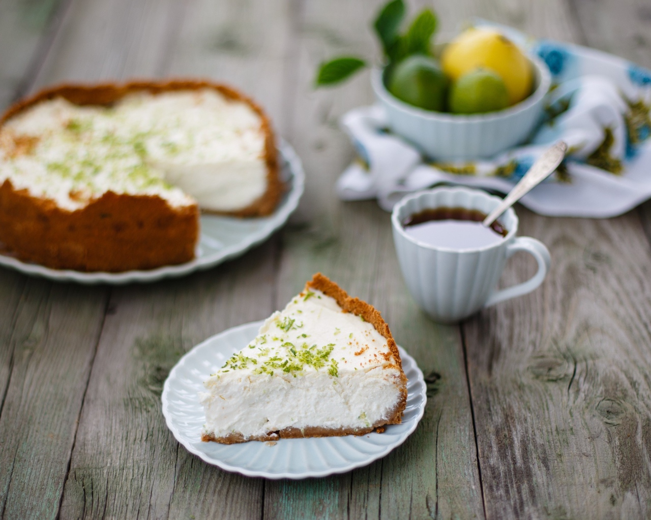 Кусок чизкейка на столе с чашкой чая