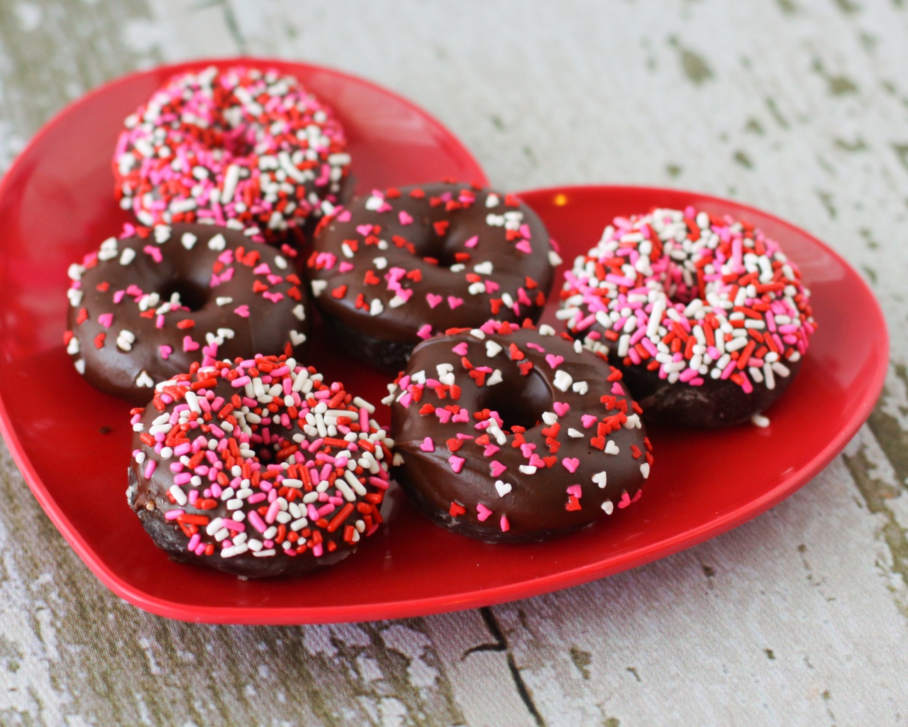 Аппетитные пончики на красной тарелке в форме сердца