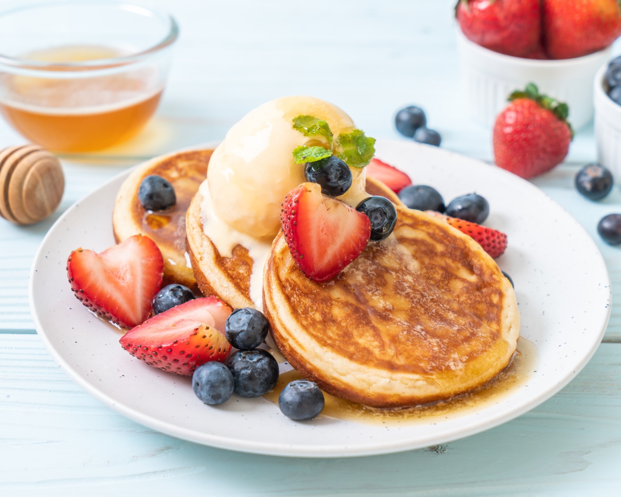 Аппетитные оладьи с мороженым, медом и ягодами клубники и черники