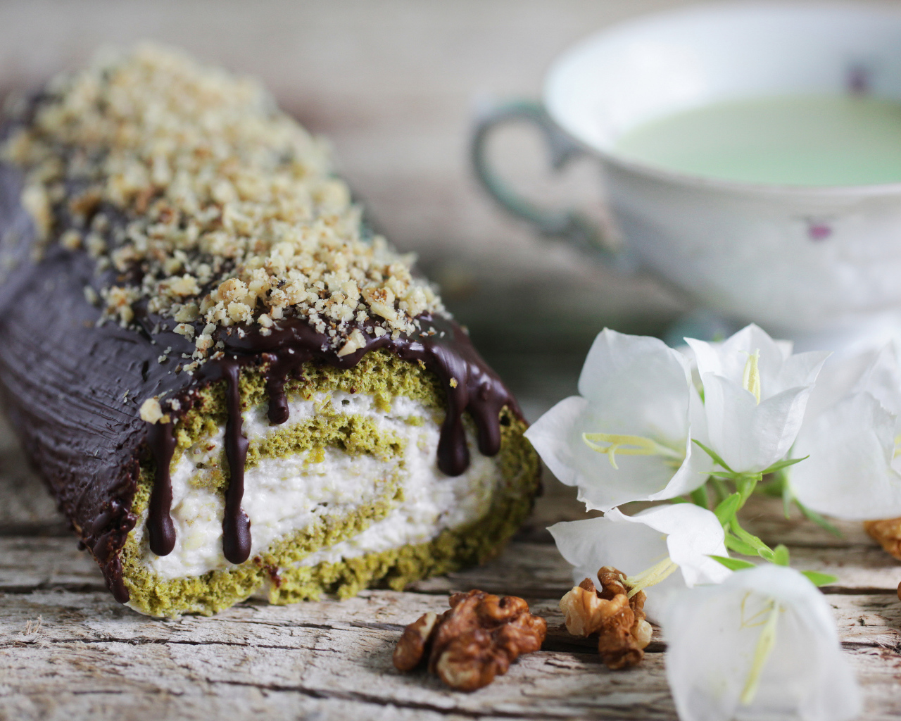 Аппетитный сладкий рулет с шоколадом на столе с белыми цветами колокольчика