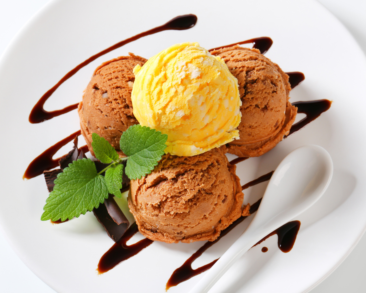 Шарики кофейного и фруктового мороженого на белой тарелке