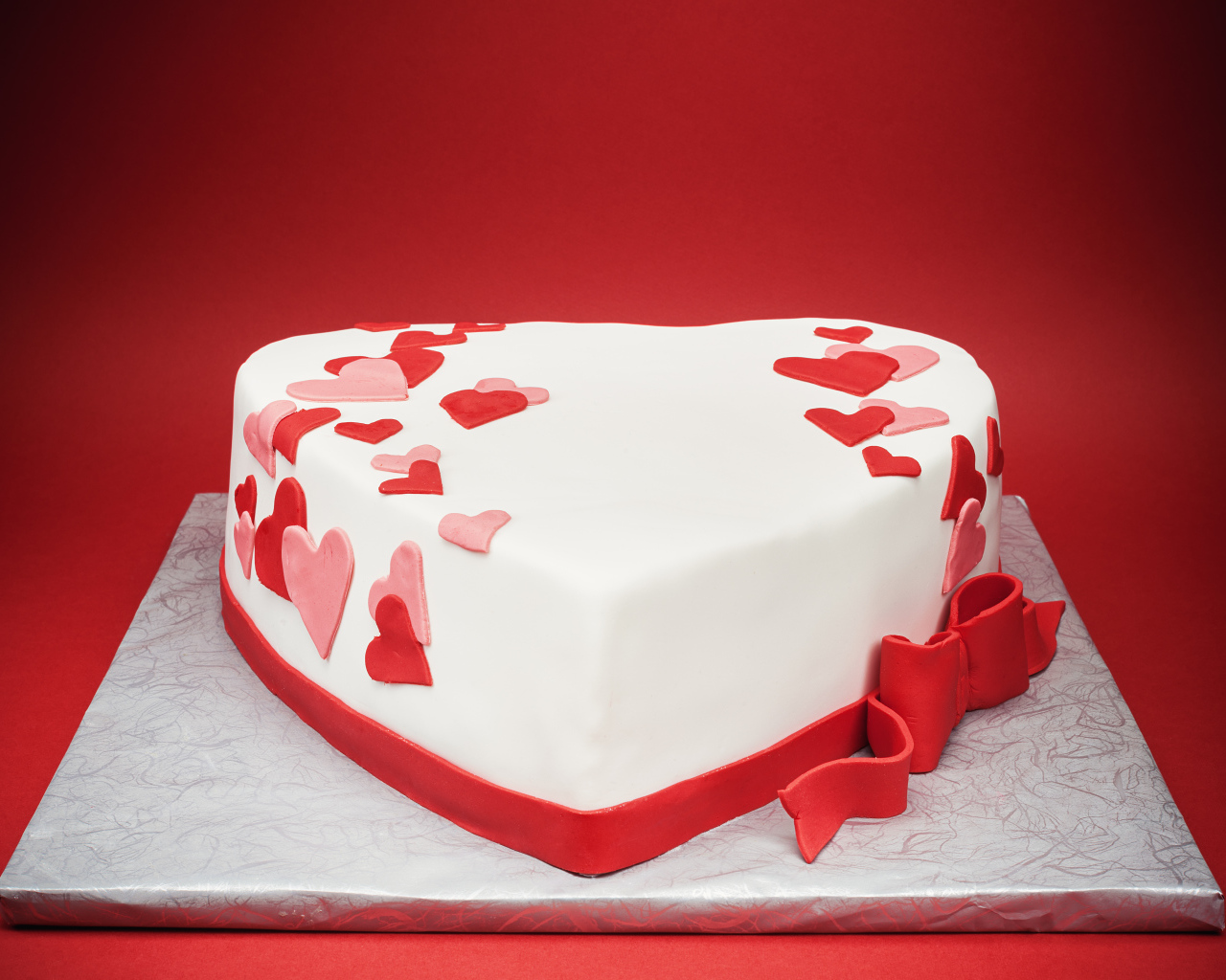 Красивый торт в форме сердца на красном фоне