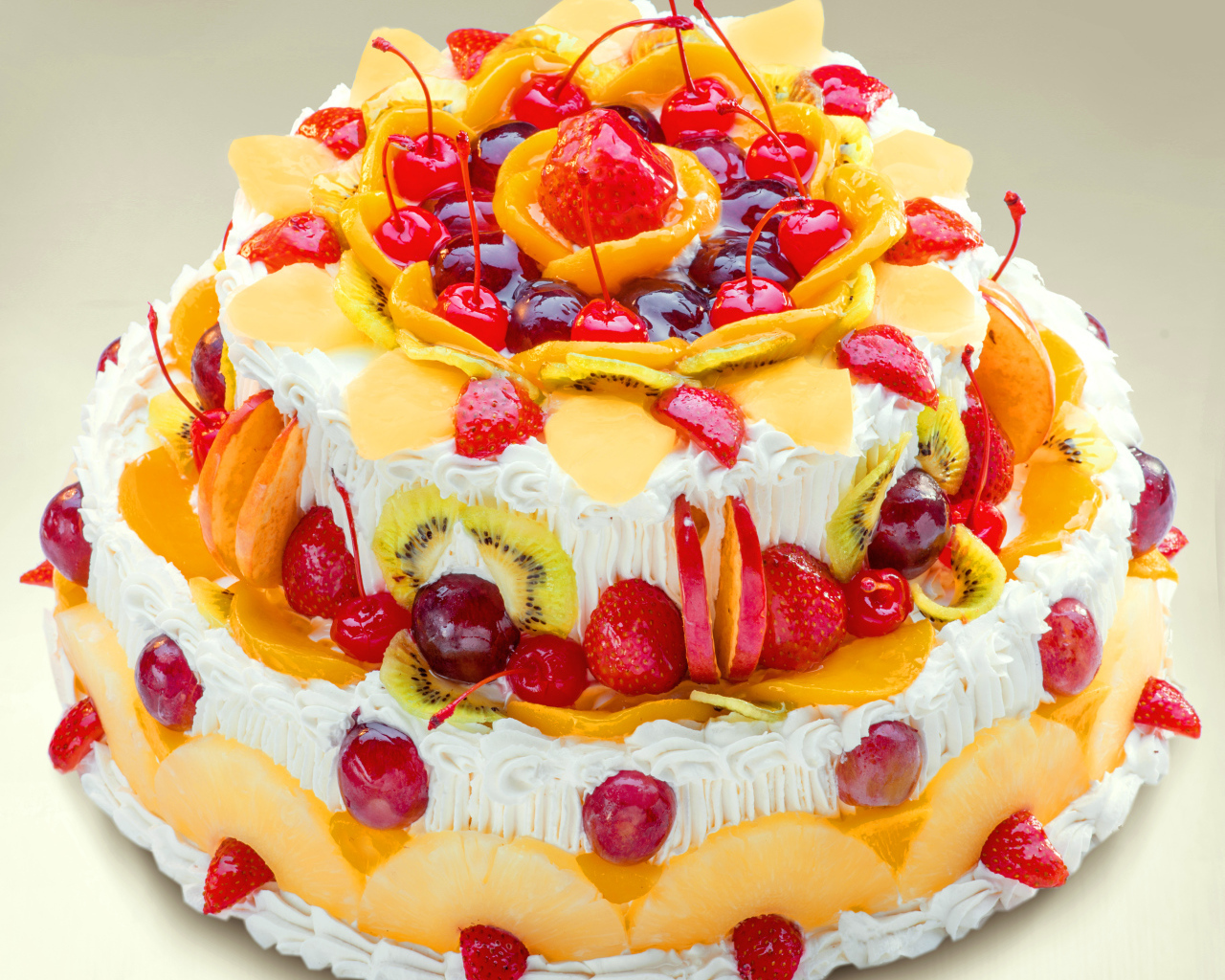 Красиво украшенный ягодами и фруктами торт с кремом
